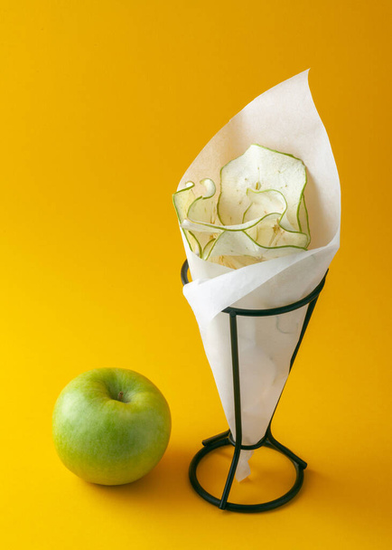 Healthy eating concept. Green apple and apple chips on a yellow background - Φωτογραφία, εικόνα