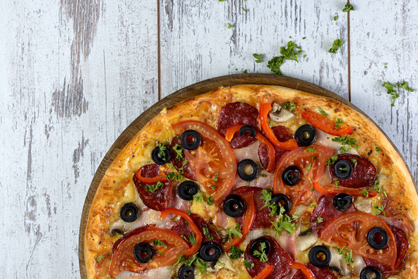 Flat lay photograph of tasty Italian pizza on grey rustic wooden background. Copy space banner. - 写真・画像