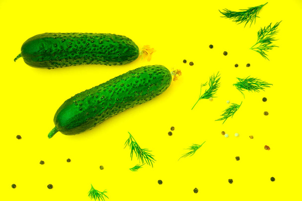 two cucumbers peppers and greens on a yellow background in the kitchen - Photo, Image