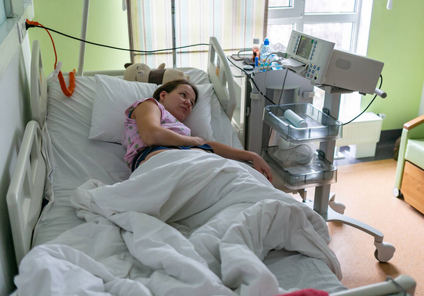 Pregnant woman feels hard contraction in a hospital labor delivery room. Concept photo of pregnancy, pregnant woman, newborn and baby. - Valokuva, kuva