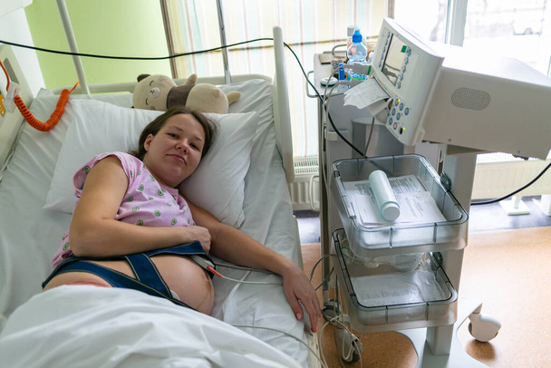 Ciężarna kobieta odczuwa silny skurcz w szpitalnej sali porodowej. Koncepcja zdjęcia ciąży, kobiety w ciąży, noworodka i dziecka. - Zdjęcie, obraz