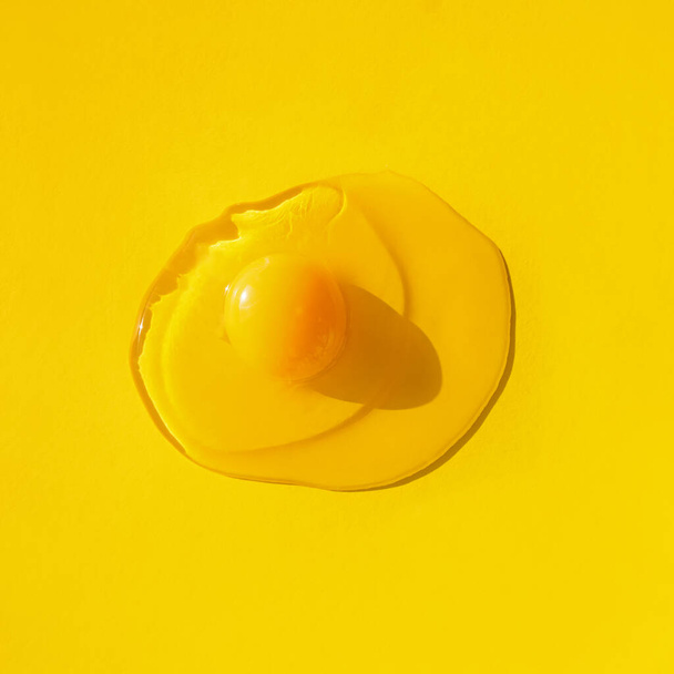Raw egg on yellow background, top view. - 写真・画像