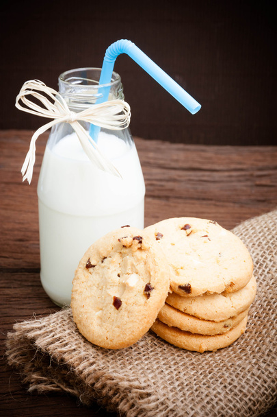cookies en fles melk op houten tafel - Foto, afbeelding