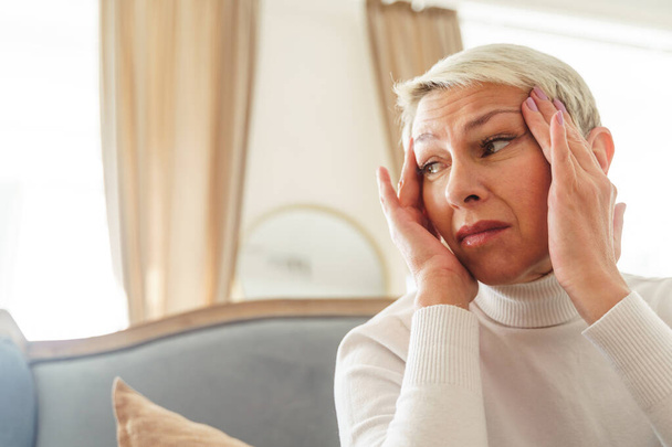 Senhora idosa triste que sofre de uma dor de cabeça
 - Foto, Imagem