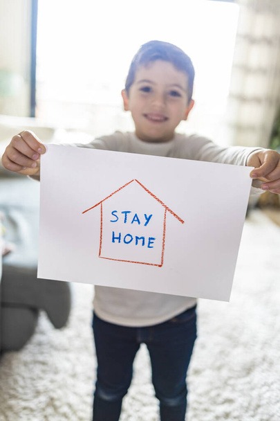 Малыш с рисунком "Оставайся дома". Коронавирусная концепция
 - Фото, изображение