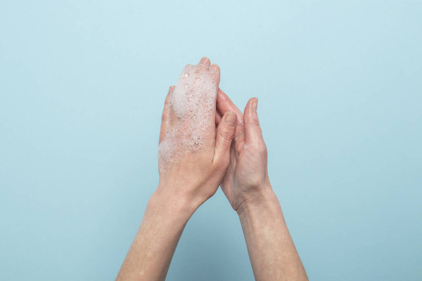 Handwas. Zeepachtige vrouwelijke handen op een blauwe achtergrond. Concept van de regels van het wassen en hanteren van handen. Bovenaanzicht, vlak lay. - Foto, afbeelding