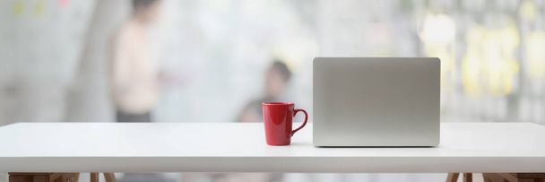 Colpo ritagliato di spazio di lavoro portatile con computer portatile, tazza di caffè e spazio copia su tavolo bianco con sfondo sfocato
 - Foto, immagini