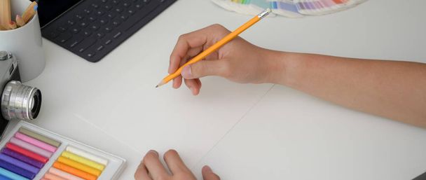Обрізаний знімок молодого чоловіка художника, що малює на папері ескіз з олівцем на мінімальному робочому просторі
 - Фото, зображення