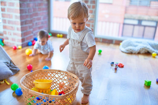 Crianças bonitas brincando em torno de lotes de brinquedos no jardim de infância
 - Foto, Imagem