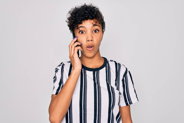 Young beautiful african american afro woman having conversation talking on the smartphone scared in shock with a surprise face, afraid and excited with fear expression - Zdjęcie, obraz
