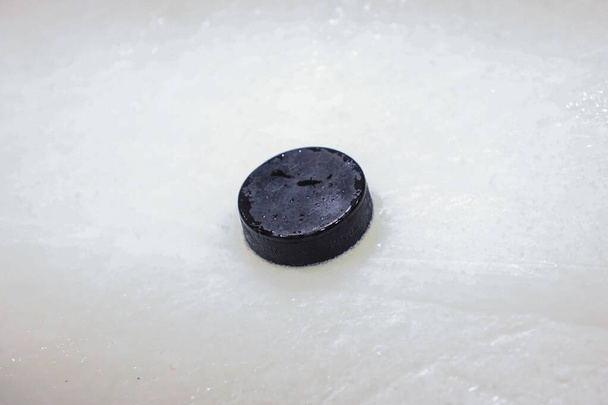 Black old ice hockey puck on ice rink. Located in Latvia. - Photo, Image