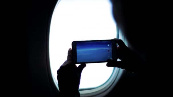 Una sagoma di persona che filma montagne e nuvole da un finestrino di un aereo
. - Filmati, video