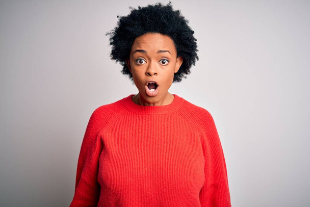 Mladý krásný afroameričan afro žena s kudrnaté vlasy na sobě červené ležérní svetr strach a šokovaný s překvapením a ohromený výraz, strach a vzrušený obličej. - Fotografie, Obrázek