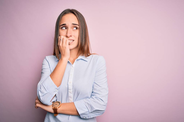 Young beautiful businesswoman wearing elegant shirt standing over isolated pink background looking stressed and nervous with hands on mouth biting nails. Anxiety problem. - Photo, Image