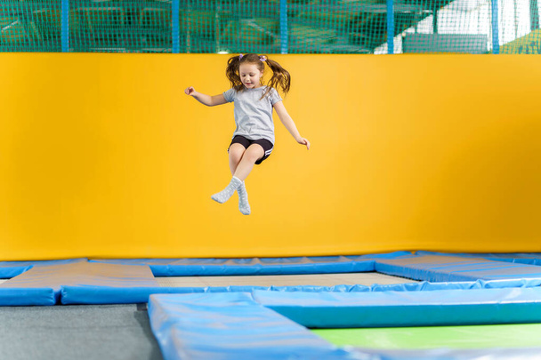 gelukkig klein meisje springen op trampoline in fitness center - Foto, afbeelding