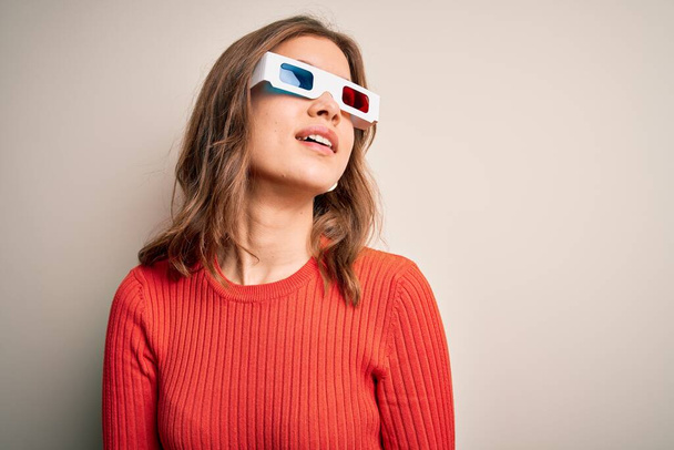 Young blonde girl wearing 3d cinema glasses over isolated background looking away to side with smile on face, natural expression. Laughing confident. - Фото, зображення