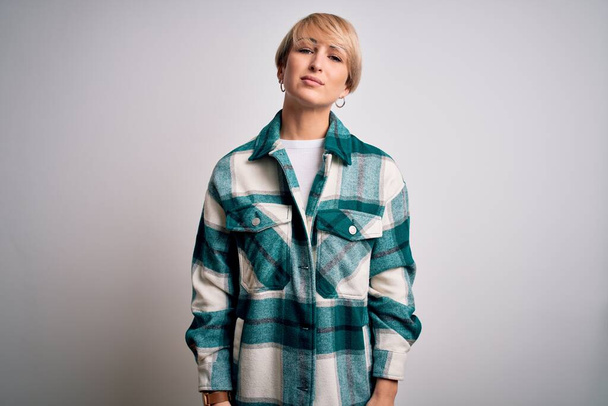 Young blonde woman with short hair wearing casual retro green shirt over isolated background Relaxed with serious expression on face. Simple and natural looking at the camera. - Foto, afbeelding