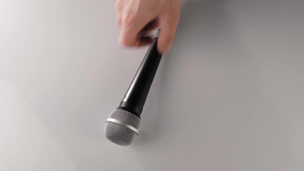 Ο άνθρωπος χέρι παίρνει ένα καρδιοειδές μικρόφωνο στο χέρι του από ένα λευκό τραπέζι. Έννοια της παραμονής στο σπίτι και να κάνει κάποια μουσική. Ελεύθερος χρόνος για ηχητική τέχνη. Στο πάνω μέρος. 4K - Πλάνα, βίντεο