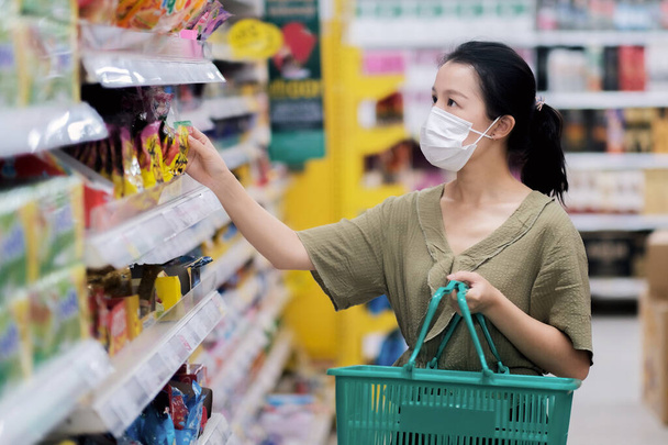 Mujeres asiáticas y máscara quirúrgica comprando algo de comida en el supermercado, crisis covid-19  - Foto, imagen
