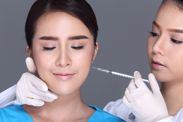 Mooie vrouw met medische schoonheid Injectie Behandeling spuit over het gezicht voor plastische chirurgie door arts, Studio verlichting grijze achtergrond geïsoleerd - Foto, afbeelding