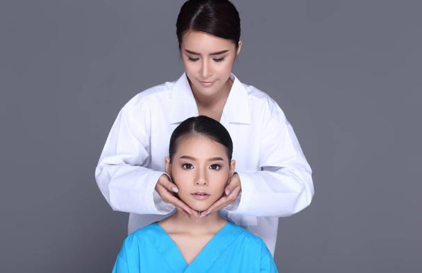 V Shape Lifting Face Checking Diagnose von Kosmetikerin Arzt, legen Sie die Hände auf das Gesicht des Patienten. Studio Beleuchtung grauer Hintergrund isoliert - Foto, Bild