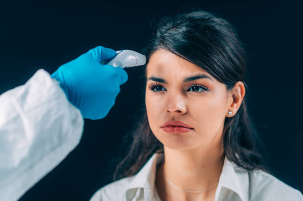 Coronavirus. Lääketieteellinen työntekijä hazmat suojaava sviitti tarkkailun kehon lämpötila, nainen suojaava naamio
 - Valokuva, kuva