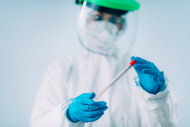 Corona virus test - Health worker in white hazmat protective suite with swab sample for PCR DNA testing  - Foto, imagen
