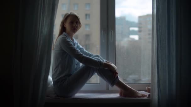 Sylwetka kobiety siedzącej przy oknie - Materiał filmowy, wideo