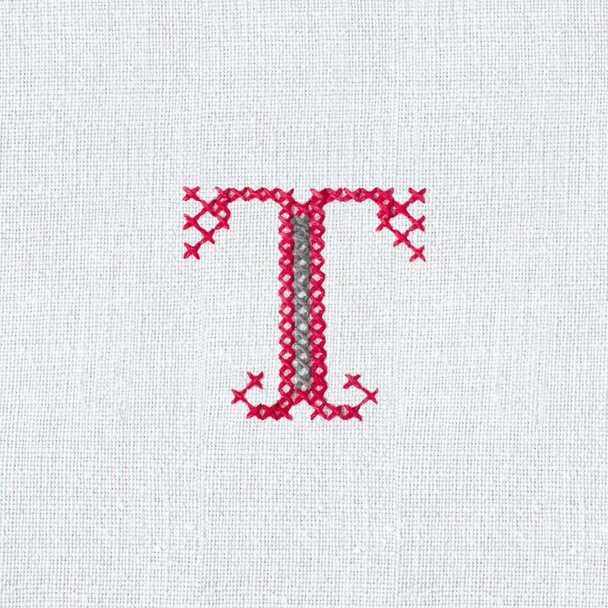 Vintage cross-stitch letter T on linen homespun fabric. Embroidered letter T close-up. Handmade art - Photo, Image