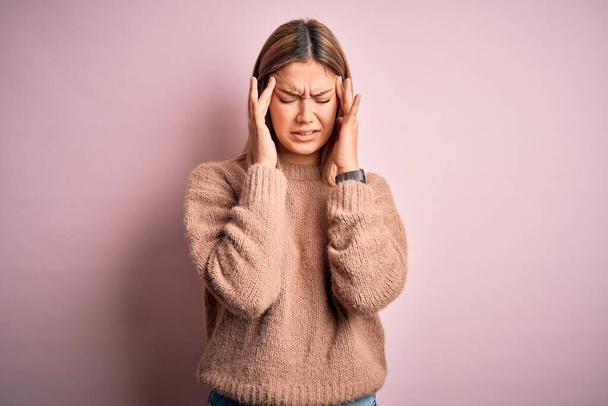 Young beautiful blonde woman wearing winter wool sweater over pink isolated background with hand on headache because stress. Suffering migraine. - Photo, Image
