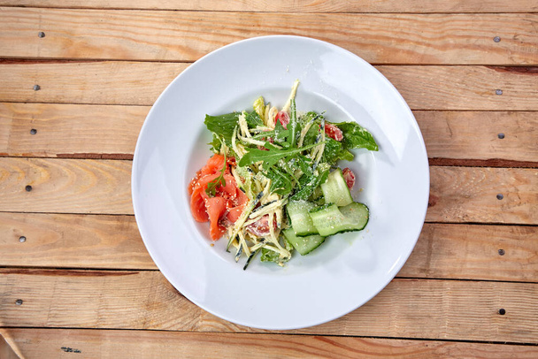 suolattu lohi tuoreilla vihanneksilla valkoisella lautasella, lähikuva  - Valokuva, kuva