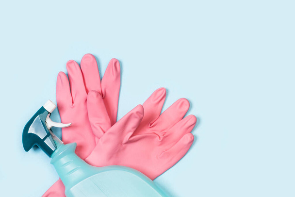 Luvas de borracha rosa e pulverizador de produto de limpeza em um fundo azul claro
 - Foto, Imagem