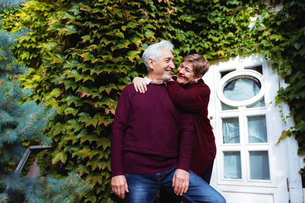 Elderly couple in love walking in the autumn park. Older people hug each other - Fotoğraf, Görsel