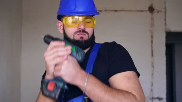 Cheerful male builder is dancing in a house with an electric screwdriver. - Video, Çekim