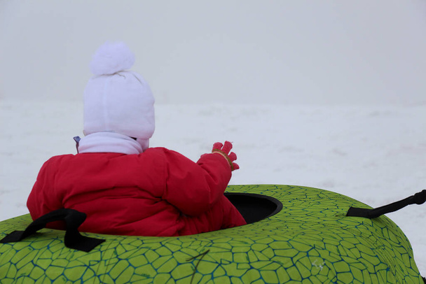 Chica en las montañas nevadas en un tubin
 - Foto, imagen