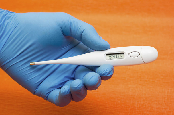 Kezében egy orvosi kesztyű tartja elektronikus hőmérő - hőmérséklet mérése, coronavirus, covid19 - Fotó, kép