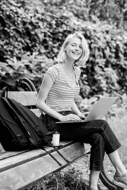 Modern student life. Surfing internet. Girl adorable student with laptop coffee cup and backpack sit bench park. Woman student work with notebook. Learn study explore. Study outdoors. Regular student - Фото, зображення