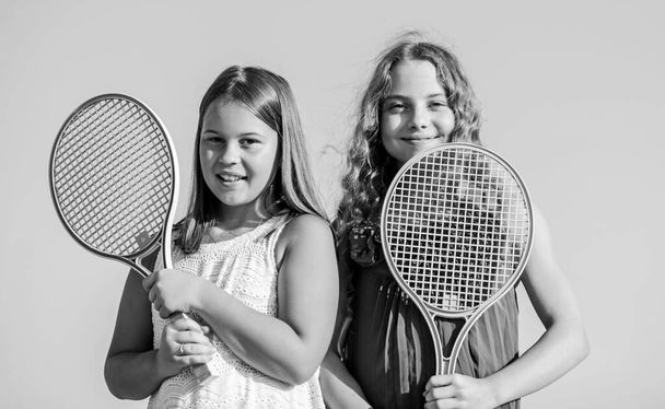 Rest time. sporty game playing. summer outdoor games. play tennis. childhood happiness and sisterhood. small girls with tennis racquet. summer sport activity. energetic children. happy and cheerful - Фото, зображення