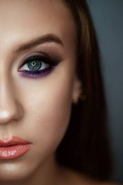 Portrait of a young woman with beautiful evening make-up on a dark background. Eyes close up. Half face - Photo, image