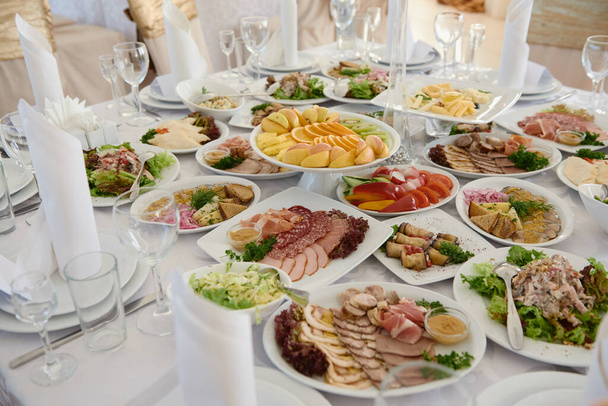 Table served for wedding banquet in restaurant. Table set with plates, white serviettes and cutlery on table, copy space. Place setting at wedding reception  - Photo, Image