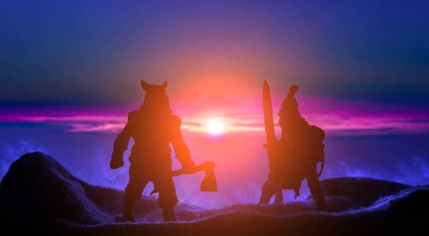 fantasia battaglia barbaro guerrieri silhouette in montagne altopiano colline in fumo su vivida luce colorata tramonto con arancio rosa sole bagliore e fantasma cielo blu sfondo, giocattolo negozio concetto foto
 - Foto, immagini