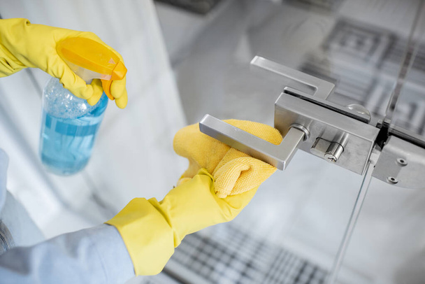 Woman cleaning door handle at home - Фото, изображение