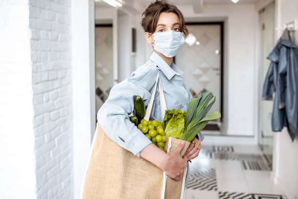 Frau in medizinischer Maske kauft Lebensmittel ein - Foto, Bild