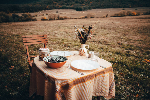 Vintage colored photo. Table prepared for lunch in autumn nature, picnic - Foto, Imagen