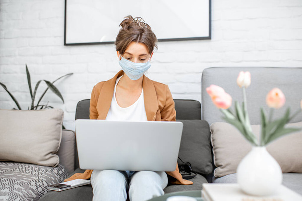 Mujer con máscara médica trabajando desde casa
 - Foto, imagen