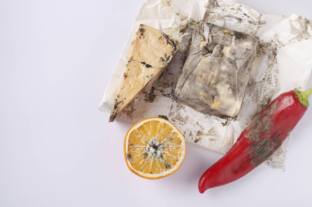 Verdorbene verdorbene Lebensmittel mit Schimmel: Orange, Pfeffer, Hartkäse und Butter auf weißem Hintergrund, Draufsicht, Kopierraum - Foto, Bild