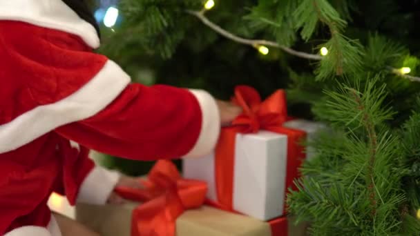 Retrato de linda niña asiática con sombrero de Santa posando cerca del árbol de Navidad
 - Metraje, vídeo
