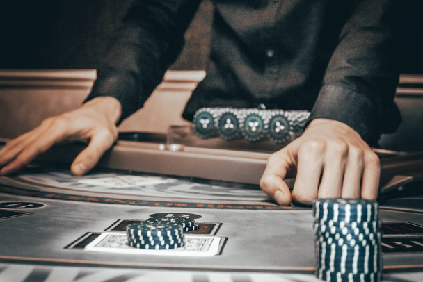 Dealer or croupier shuffles poker cards in a casino on the background of a table, chips,. Concept of poker game, game business. - Photo, Image