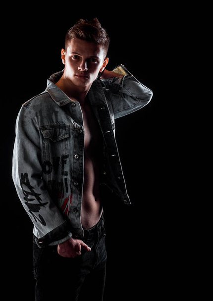 Full body shot of a fashion male model wearing stylish clothes against black wall - Valokuva, kuva