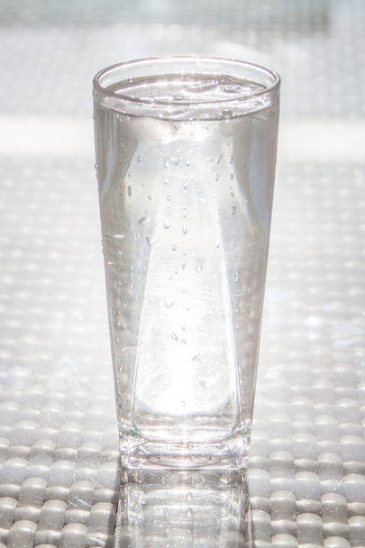 Icy Cold Glass of Water with Water Drops Reflecting on Glass Table - Φωτογραφία, εικόνα